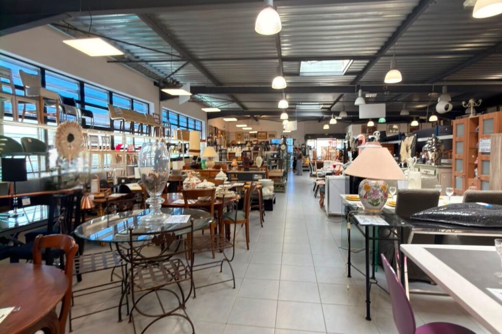 Intérieur spacieux d'un magasin de dépôt-vente avec mobilier, décoration et objets d'occasion exposés sous éclairage naturel